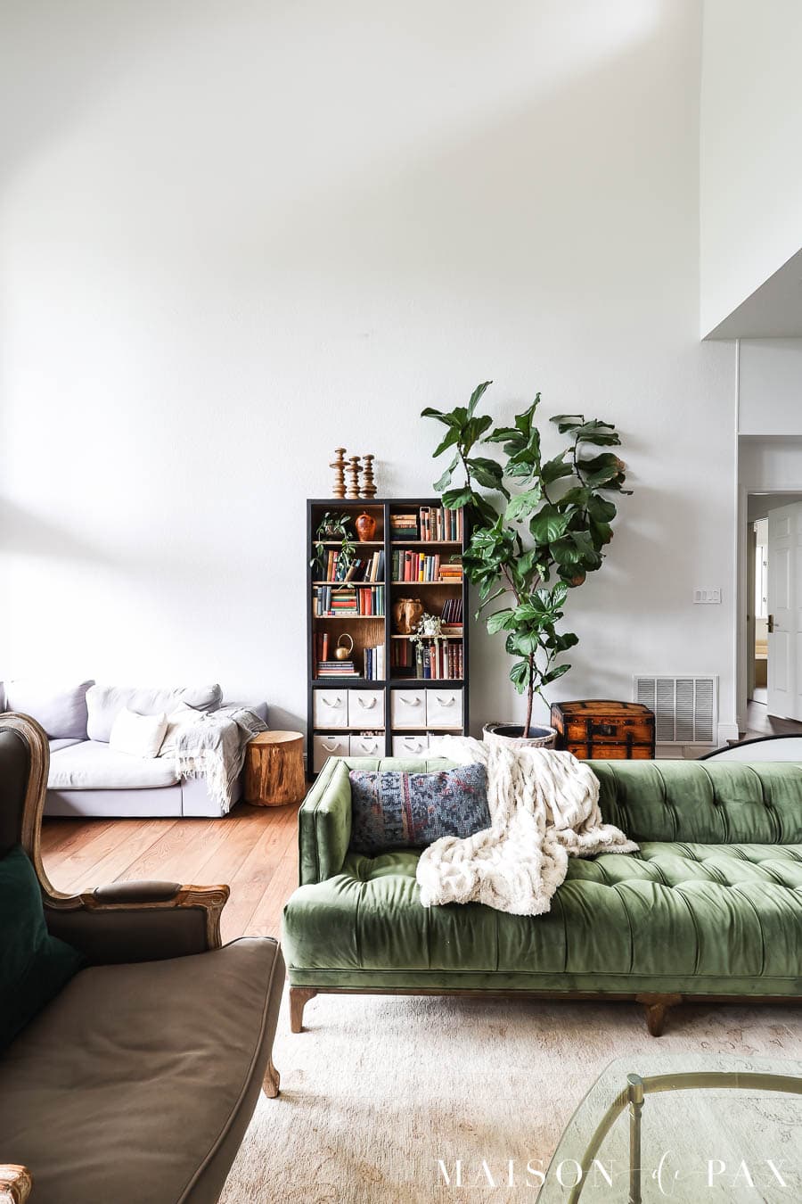 light streaming into a high ceiling living room with white walls and eclectic furniture