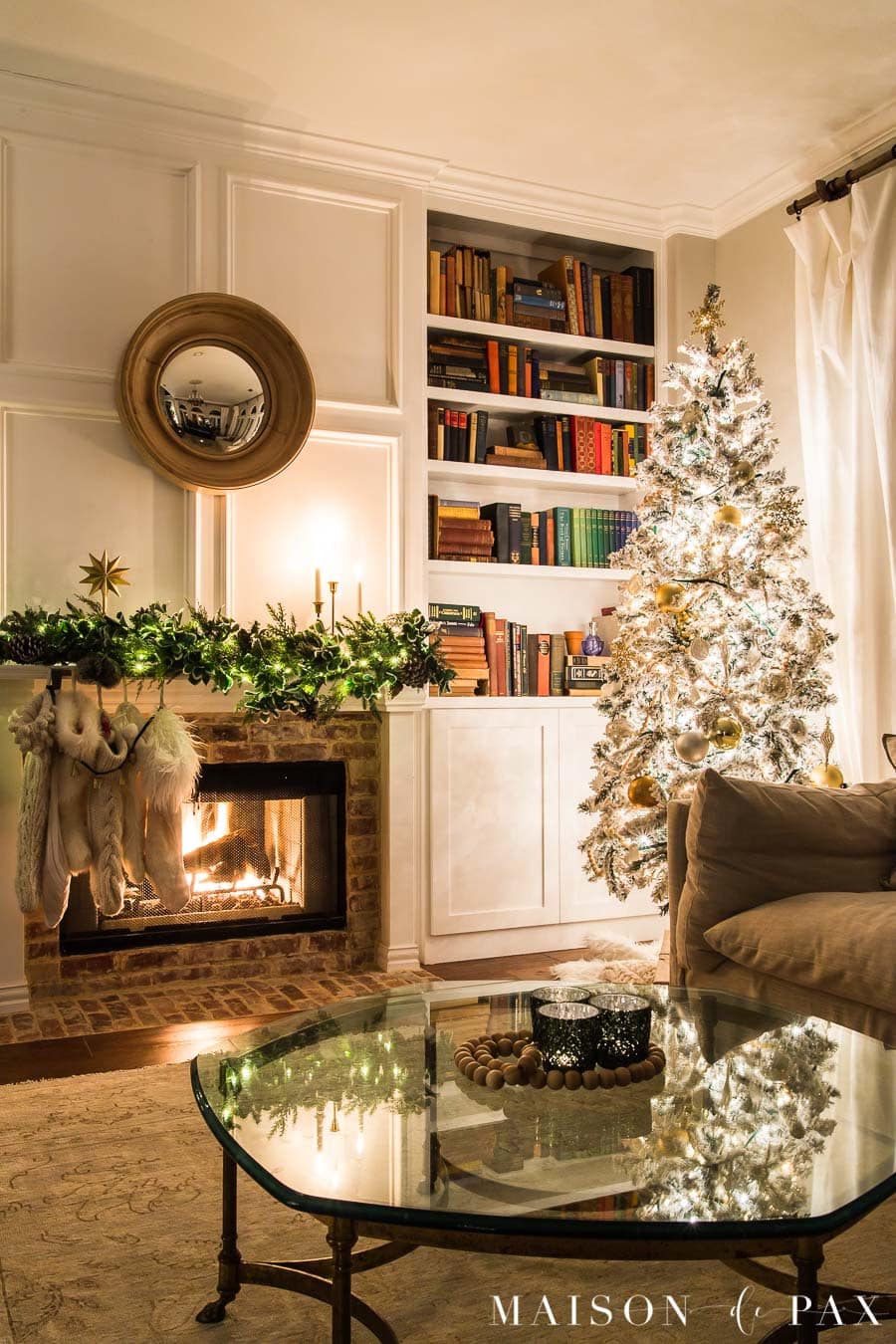 Flocked Christmas tree beside bookcase and fireplace | Maison de Pax