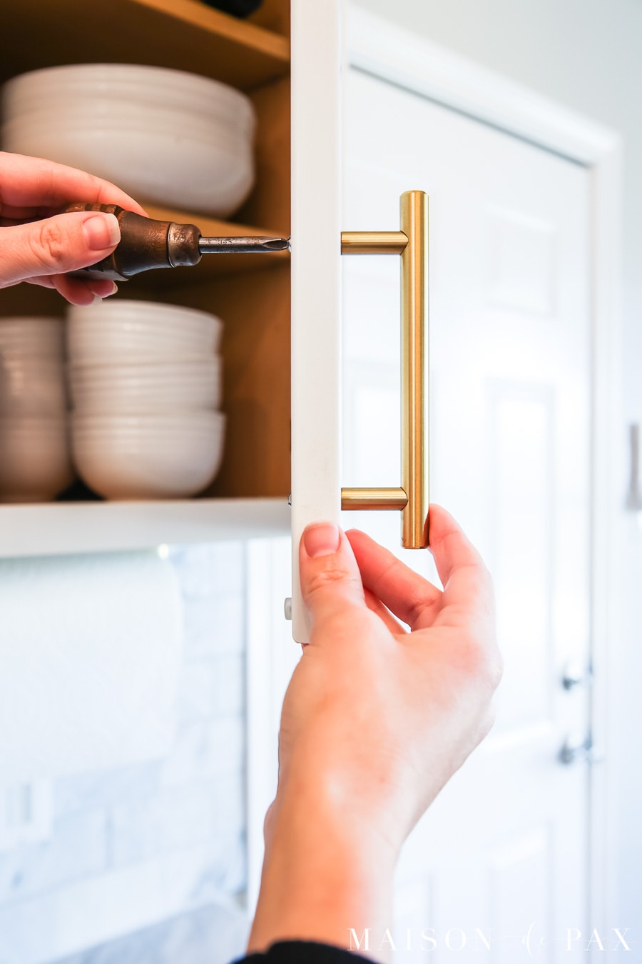 installing kitchen cabinet hardware with a screwdriver