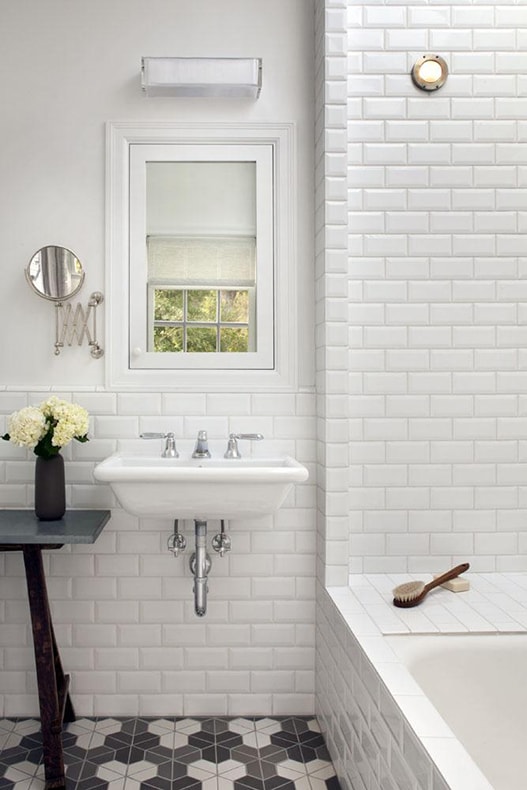 Remodelista: classic white cottage bathroom with beveled white subway tile and patterned black and white concrete tile floors