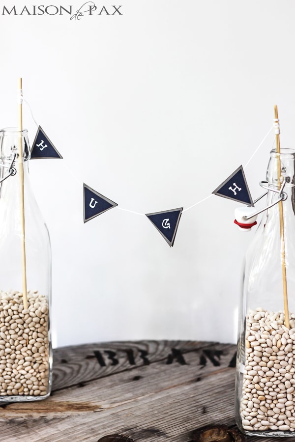 glass bottles hold navy and gray bunting with white letters | Maison de Pax