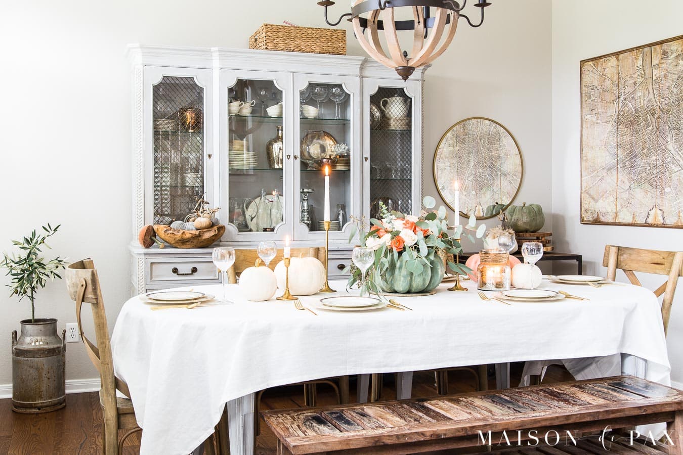 French country dining room with modern elements such as a round brass mirror.