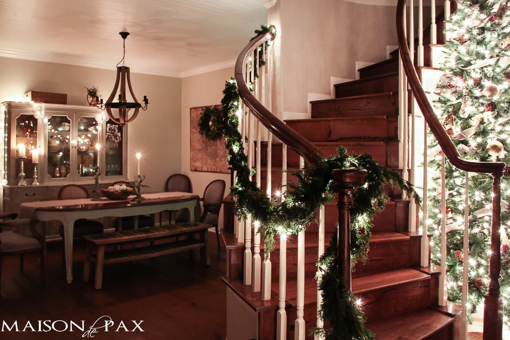 lighted garland on stairs, big christmas tree with white lights
