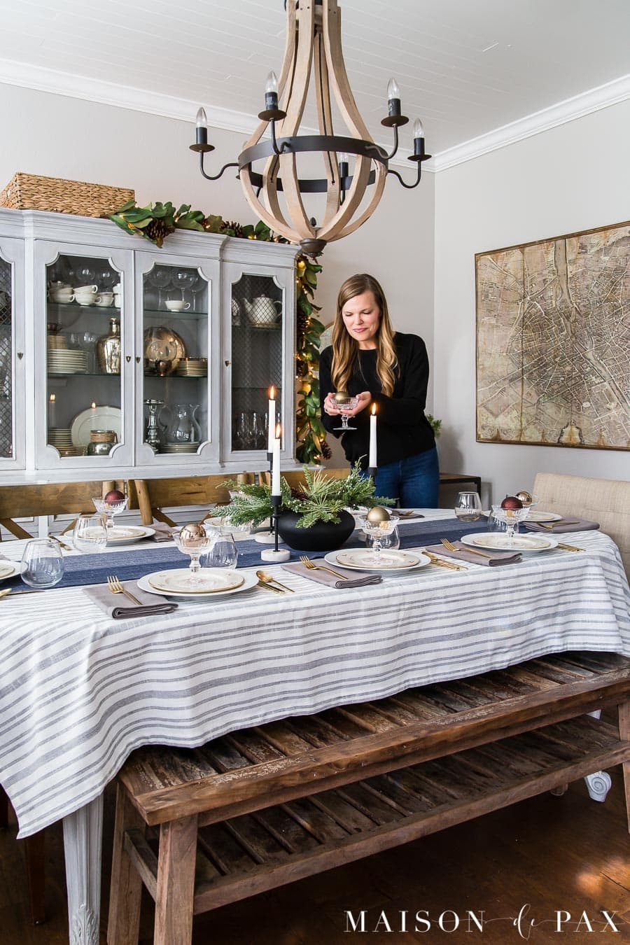 woman decorating dining room with Christmas table decorations