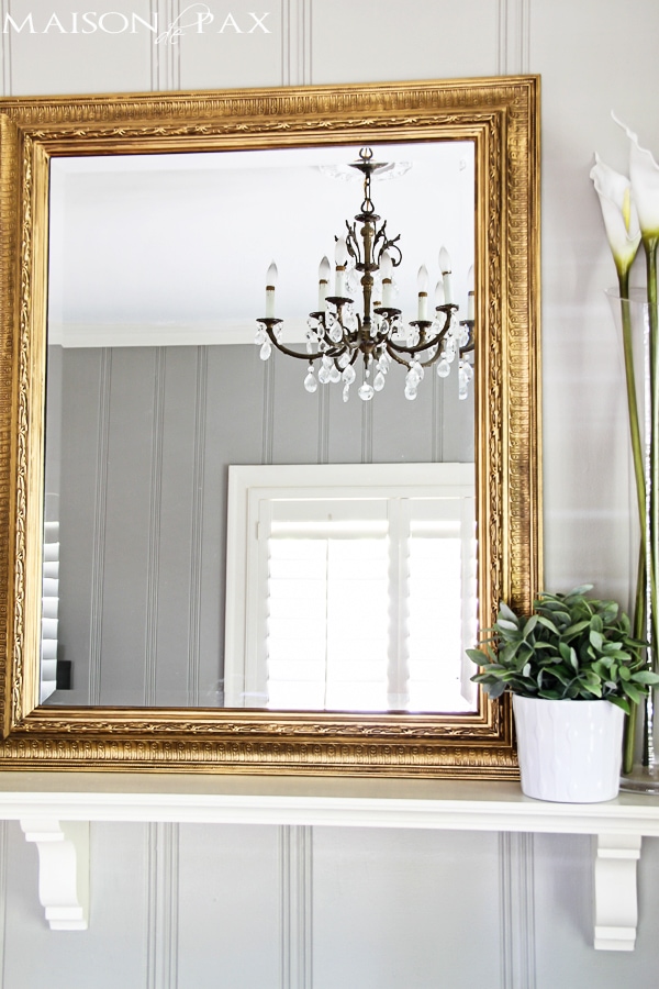 gilded mirror over vintage fireplace with crystal chandelier