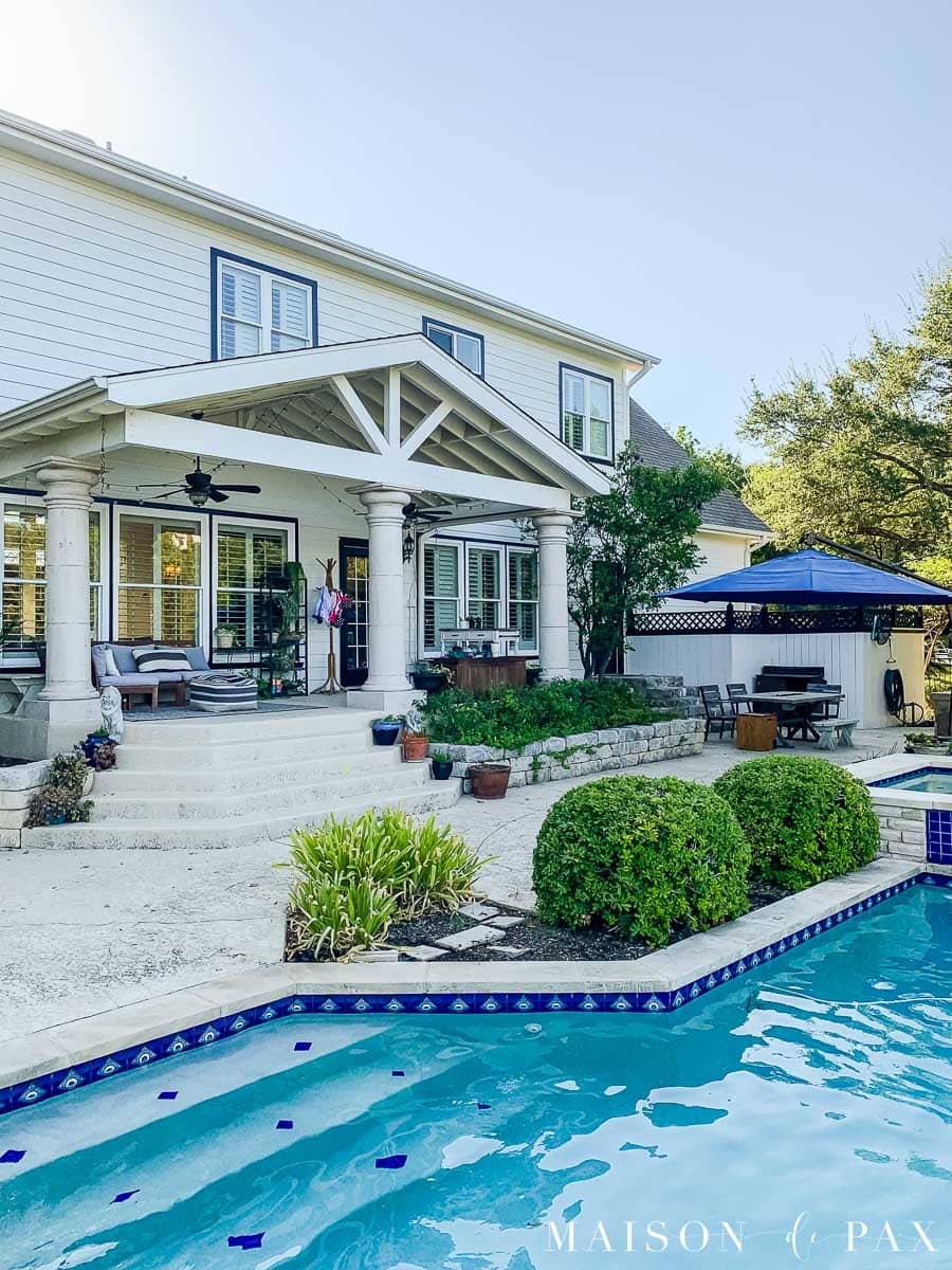 blue pool behind white house with black trim | Maison de Pax
