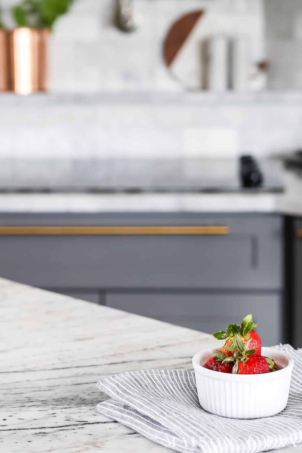 Close-up of a bowl of strawberries on a gray and white marble countertop- Maison de Pax