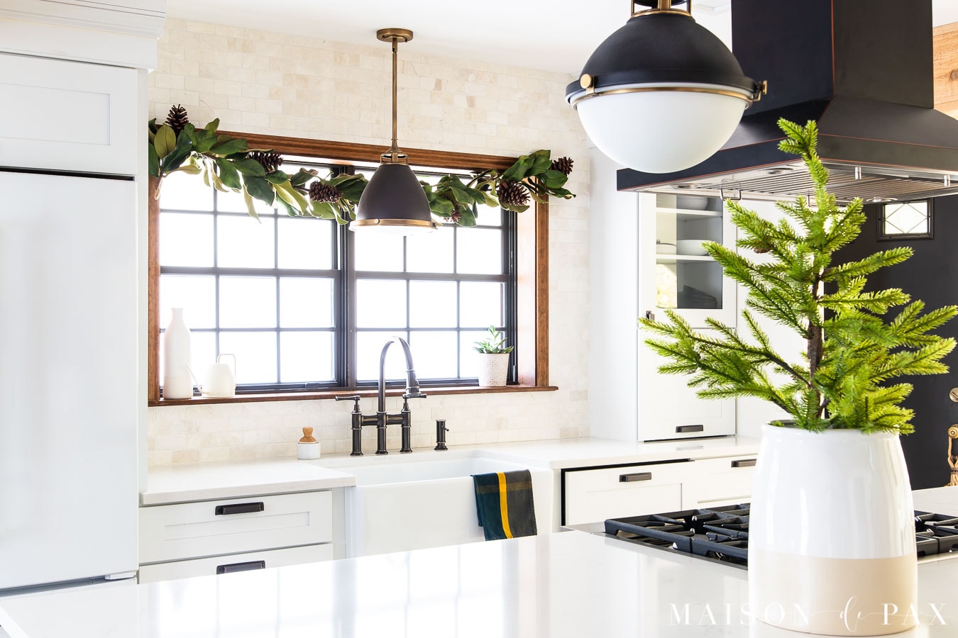 magnolia garland over farm sink with green plaid dish towel and mini tree on kitchen island | Maison de Pax