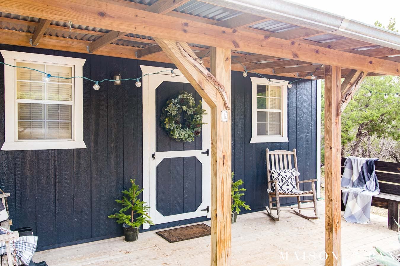 string lights on the front porch of a black and white tiny house