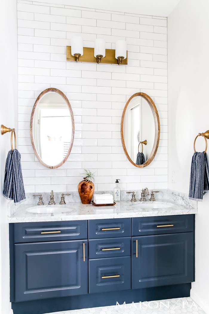 navy and brass Jack and Jill bathroom with white subway tile, gold lighting and hardware, and a polished nickel sink faucet - Maison de Pax