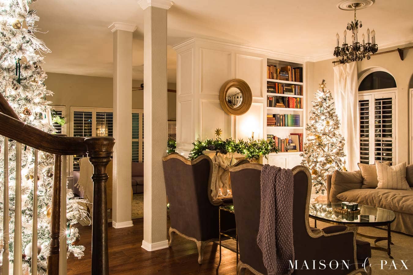 Living room with two Christmas trees and a fireplace decorated with garland | Maison de Pax