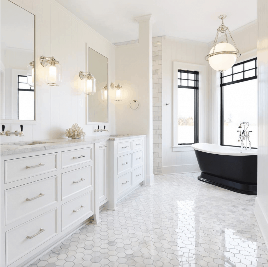 black freestanding tub in large marble bathroom