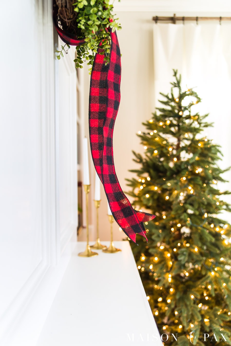 red buffalo check ribbon on green wreath by green christmas tree | maison de Pax