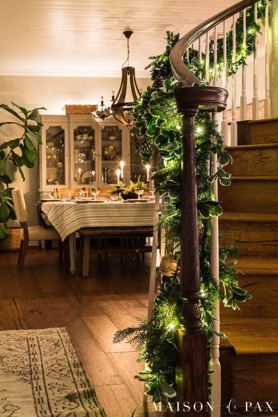 stair garland with Christmas lights and dining room lit by candlelight