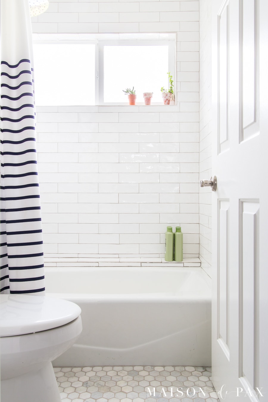 white tiled shower with navy and white striped shower curtain