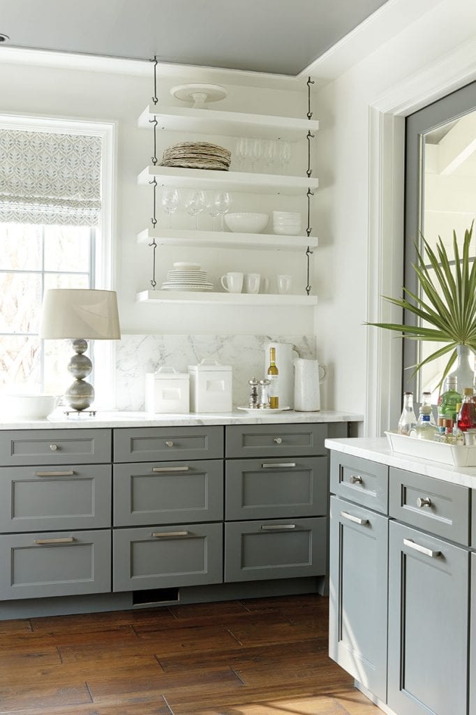 kitchen with gray lower cabinets and open white floating shelves