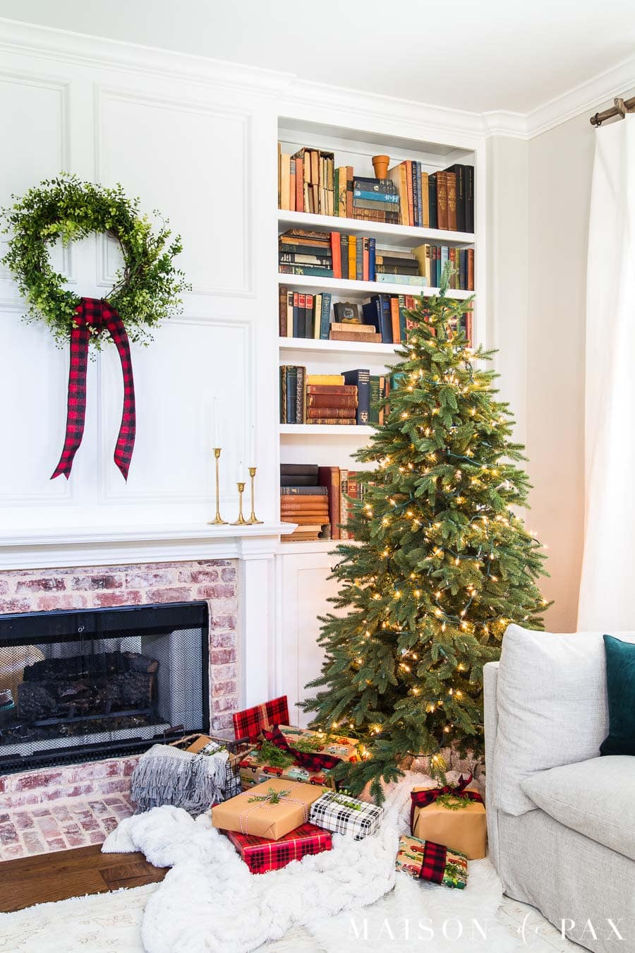 brick fireplace and white bookcase with red and green christmas decor | Maison de Pax