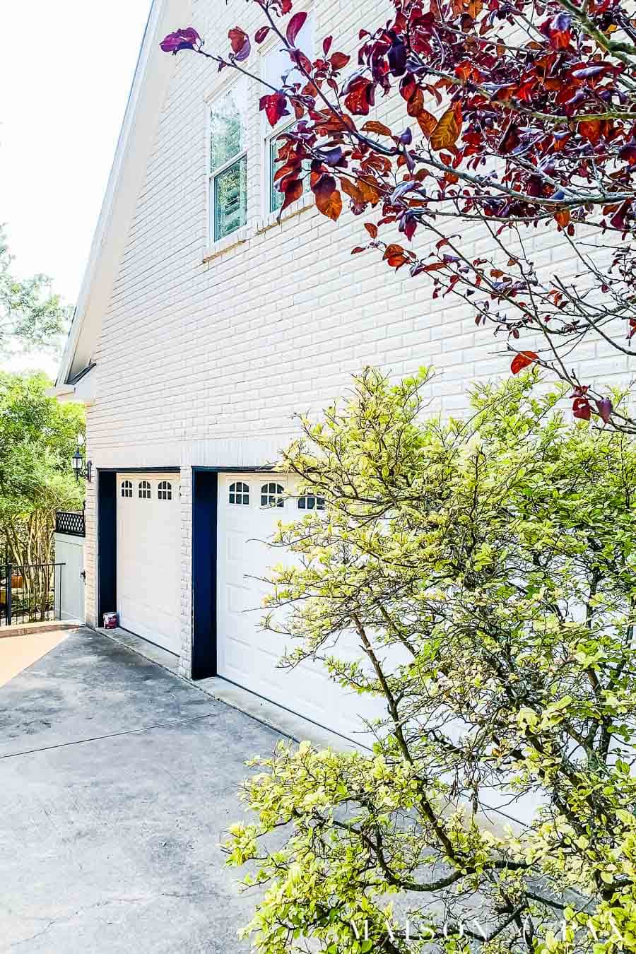 white brick house with white garage doors and black trim | Maison de Pax