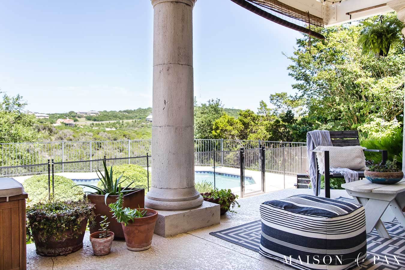 patio with large columns overlooking a pool and green hill country view | Maison de Pax