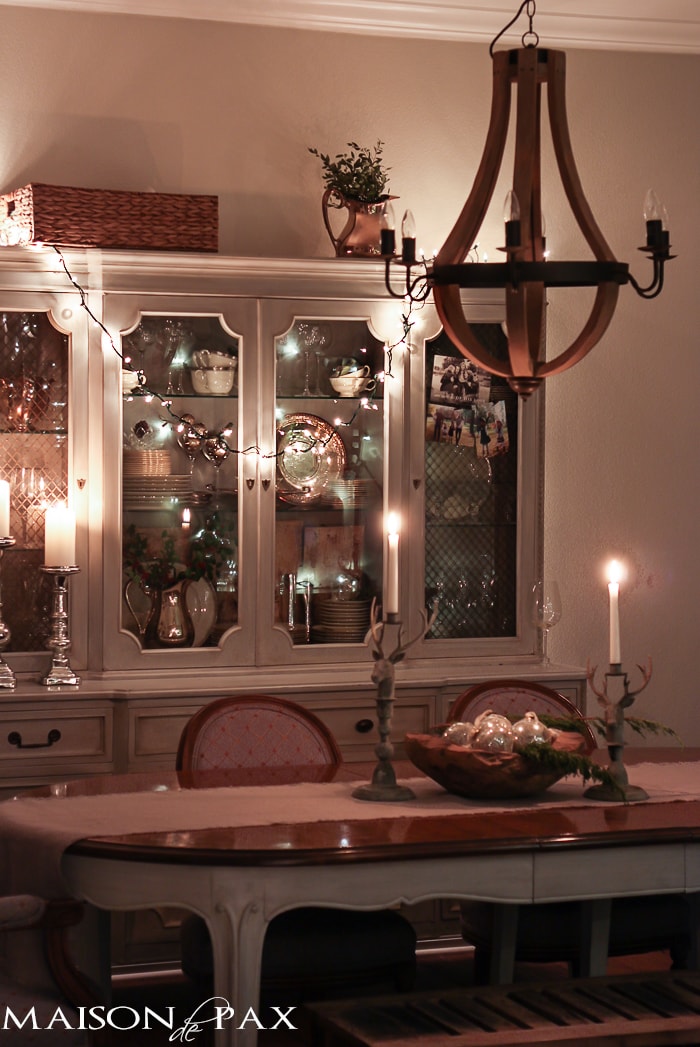 holiday decorating: Christmas table with reindeer candlesticks, string lights on china cabinet