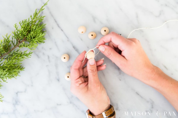 tie large wood bead onto string or jute to make garland