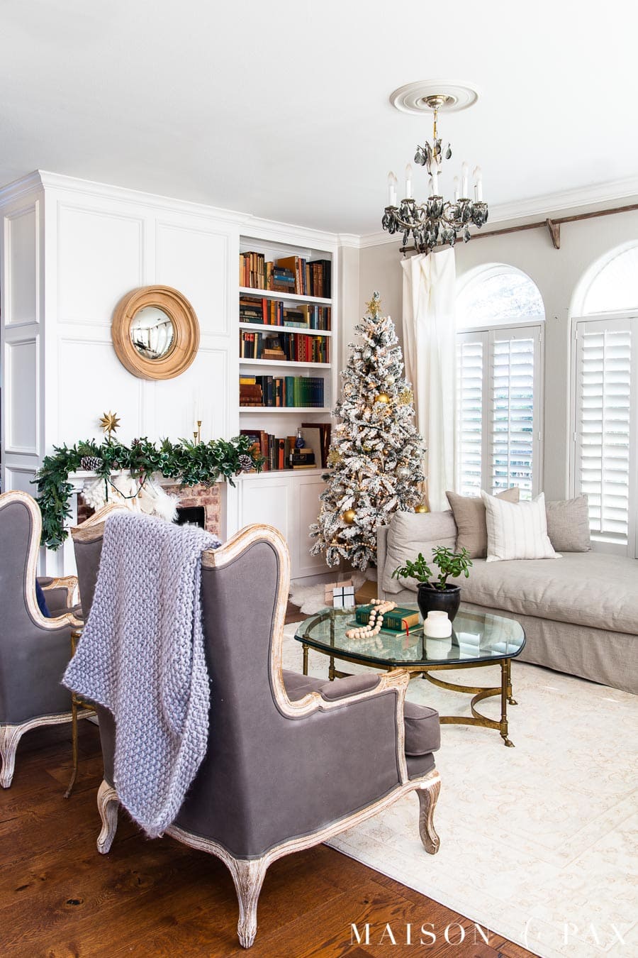 traditional living room with flocked christmas tree and green mantel garland | Maison de Pax