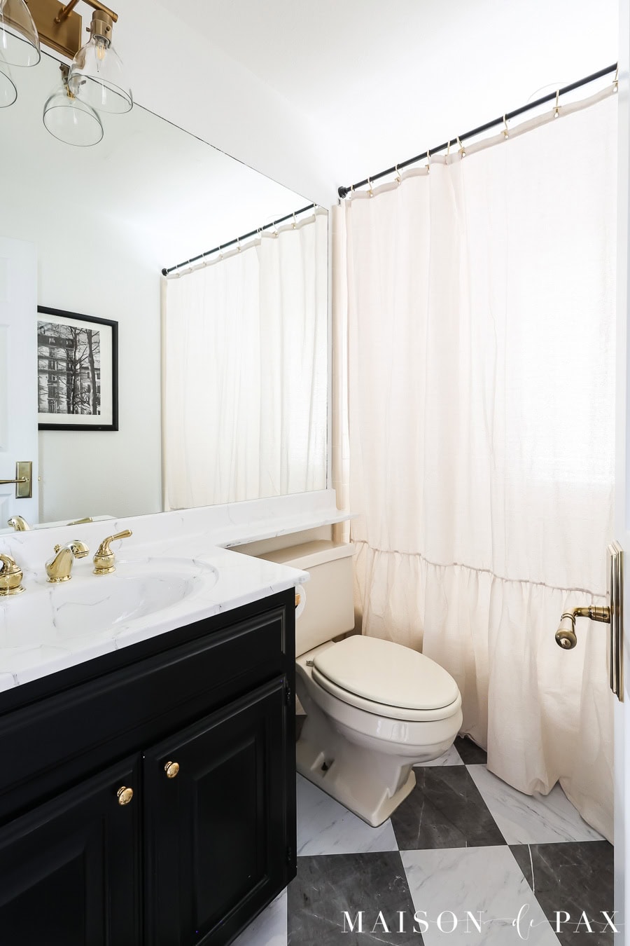 small bathroom with black and white harlequin floor, black vanity, and ruffled linen curtain