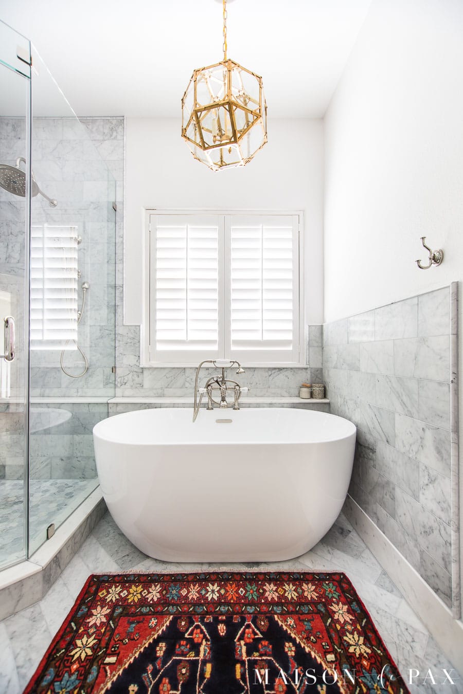 marble bathroom with white freestanding transitional tub and vintage rug | Maison de Pax