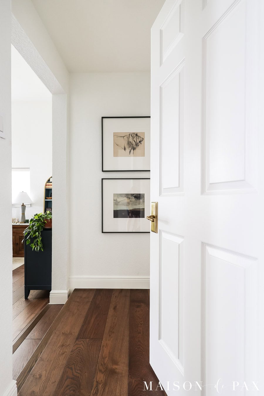 white walls, gold door hardware, medium brown white oak flooring, tall baseboards