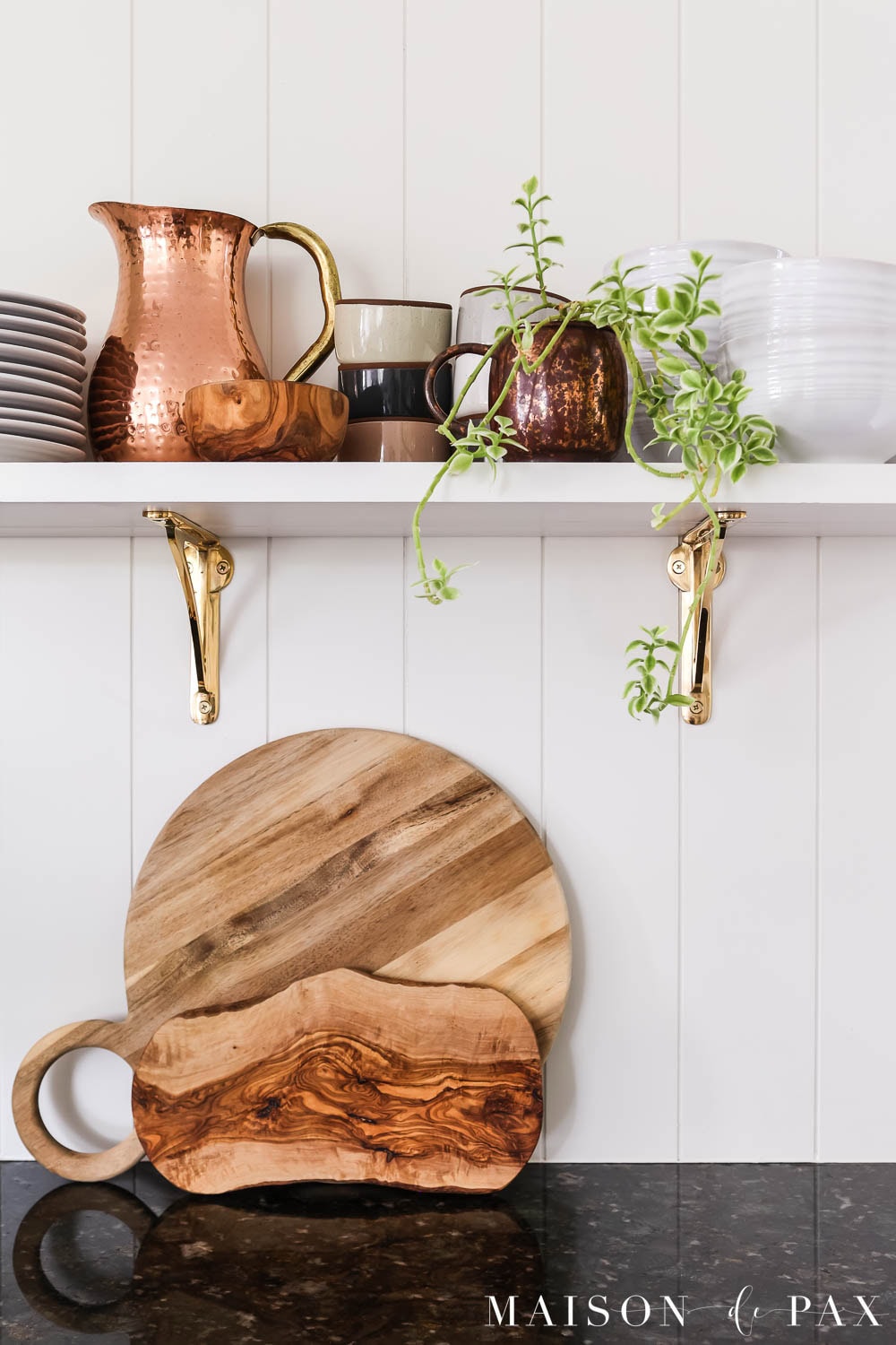 cutting boards, dishes, copper pitcher, and an ice plant on an open shelf in a kitchen