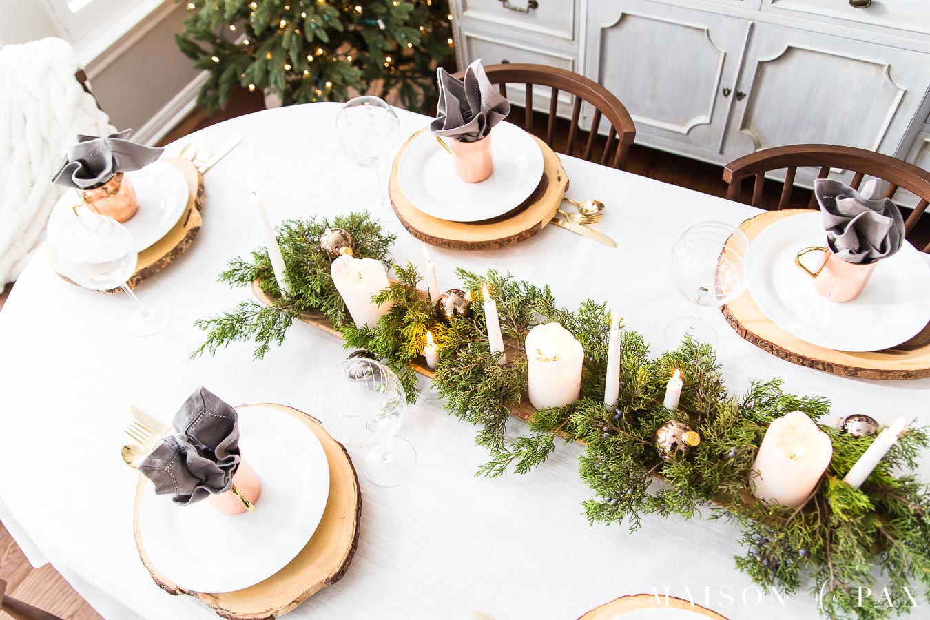 rustic wood log slice chargers under simple white plates create a rustic modern tablescape for the holidays