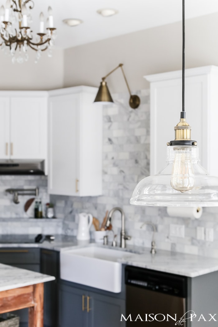 glass and brass industrial pendant light is perfect for a modern touch in this marble white kitchen #kitchenlighting
