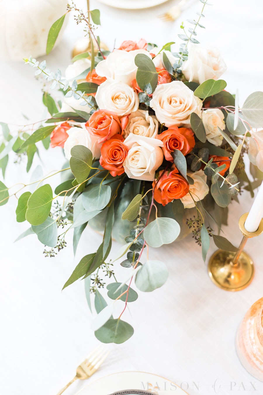 white and coral roses with seeded eucalyptus centerpiece