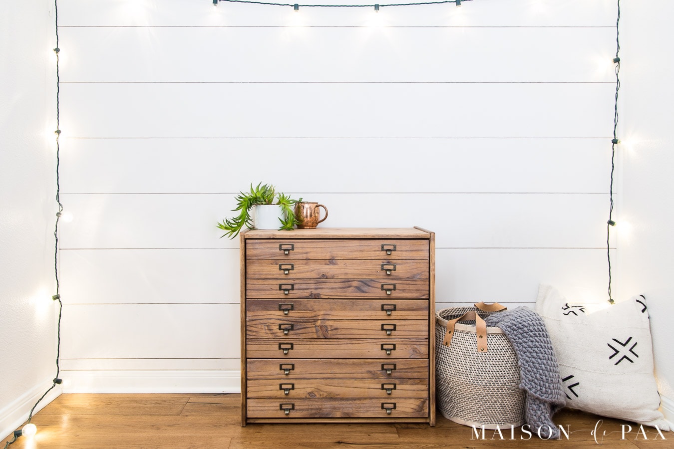 white plank wall with globe lights and antique printer's cabinet dresser