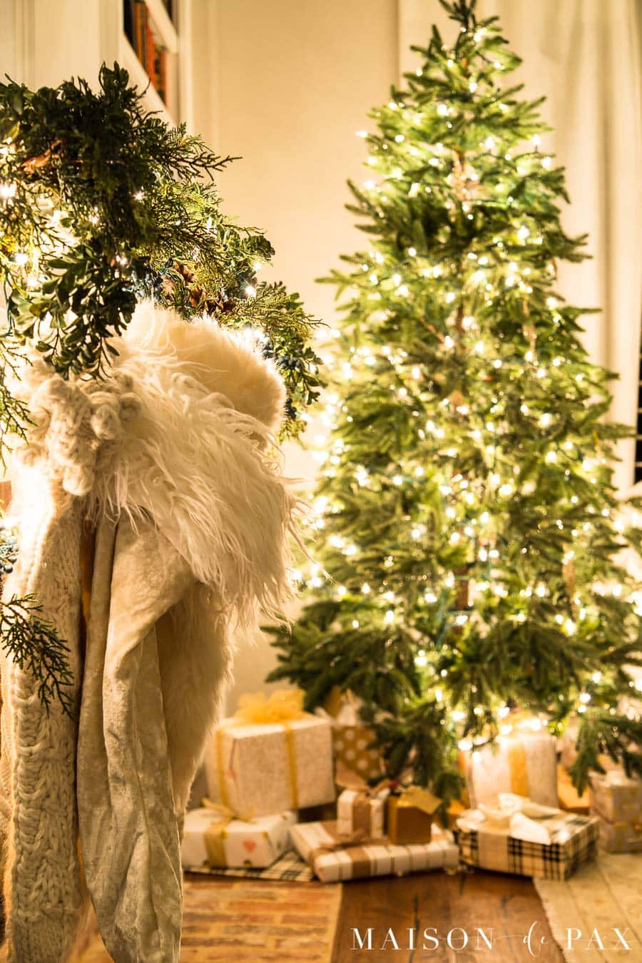 white fur stockings and beautifully wrapped presents under almost naked Christmas tree at night | Maison de Pax