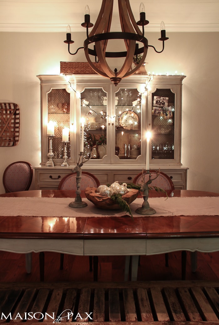 holiday decorating: Christmas table with reindeer candlesticks, string lights on china cabinet