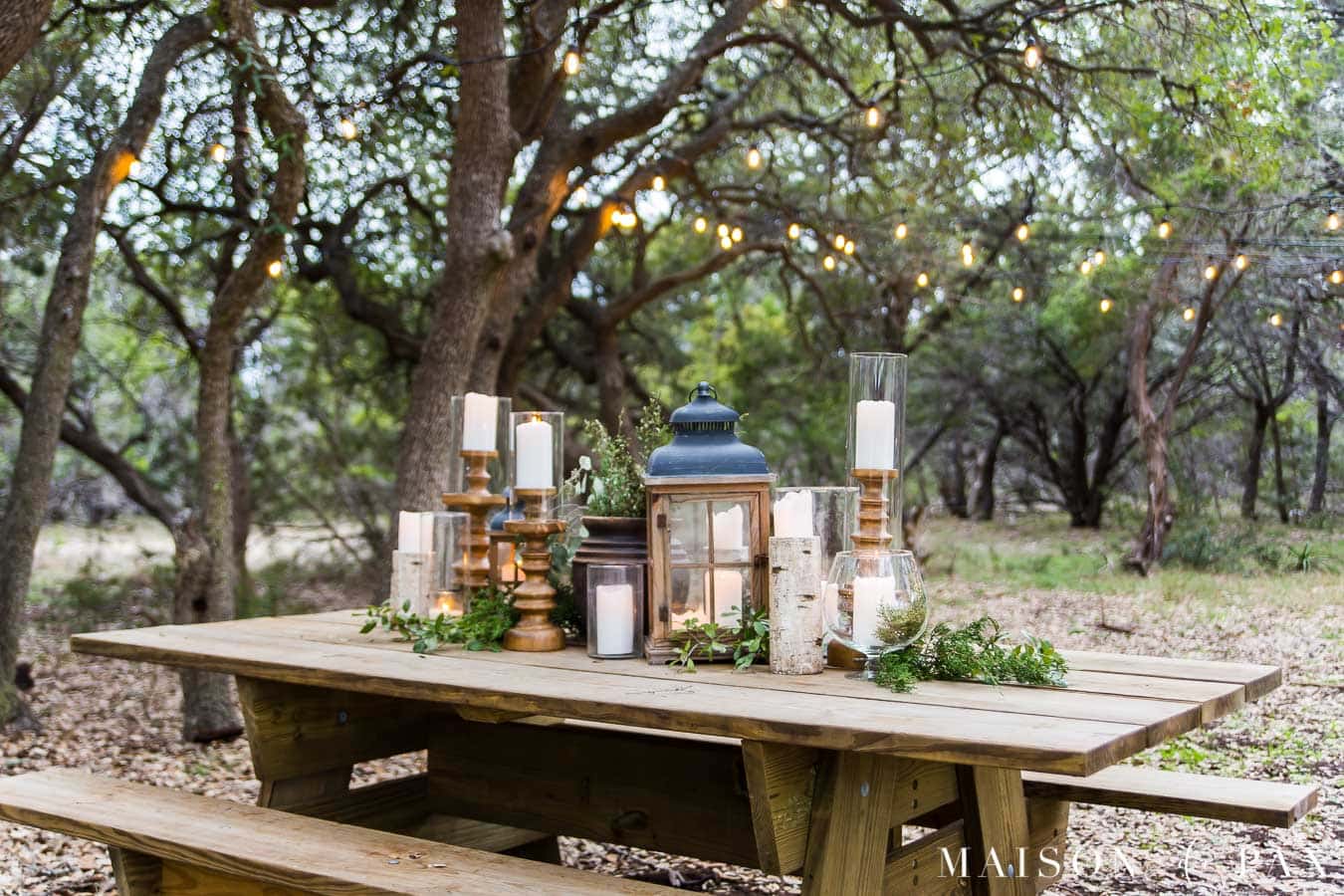 big wooden picnic table with elegant green and white centerpiece | Maison de Pax