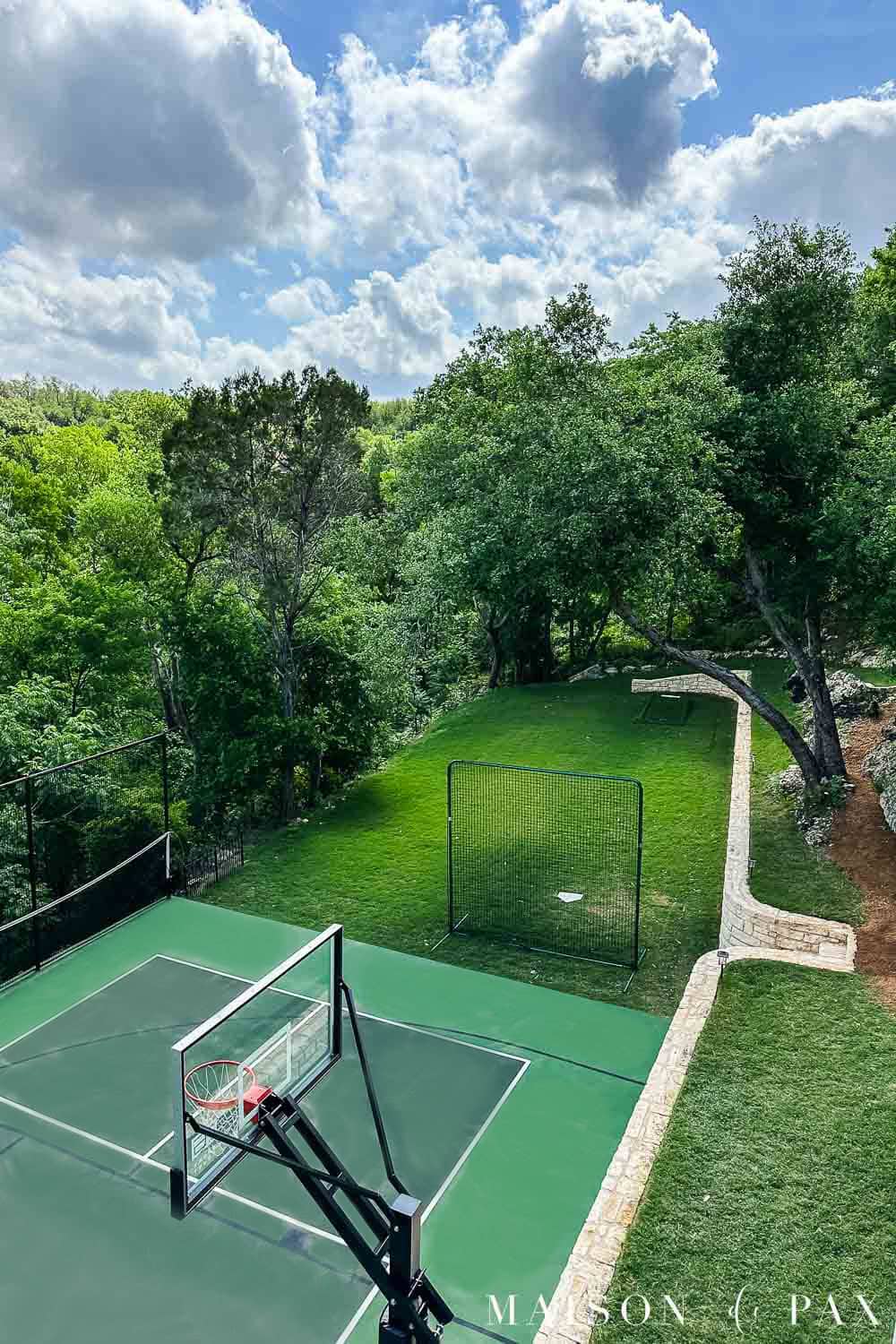 backyard with sport court, lawn, retaining wall, and granite paths