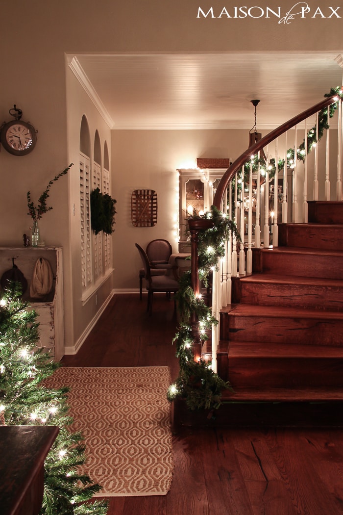 holiday decorating: mini Christmas tree, lighted garland on stairs, string lights on china cabinet