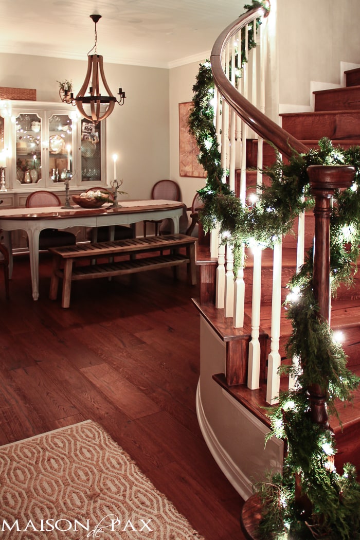 holiday decorating: Christmas table with reindeer candlesticks, string lights on china cabinet, lighted garland on stairs
