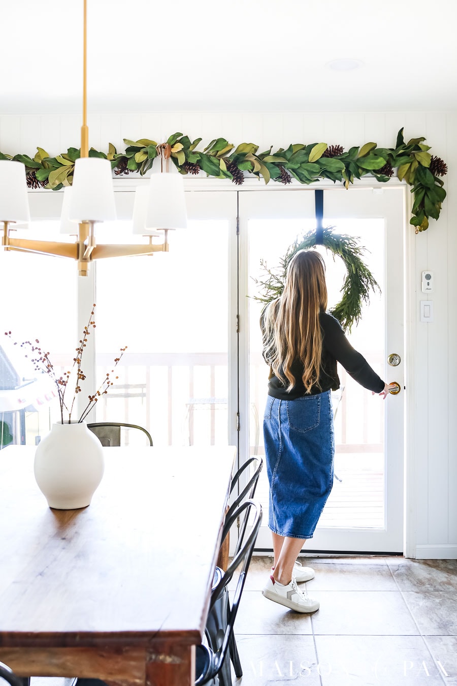 magnolia garland above doorway and wreath on door with ribbon christmas decor ideas