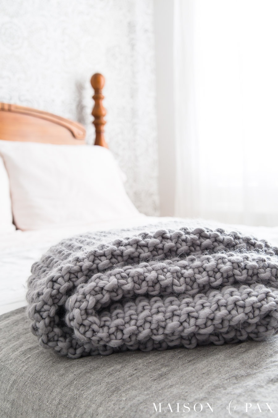 gray wool knit blanket on a white bed with an antique wood frame
