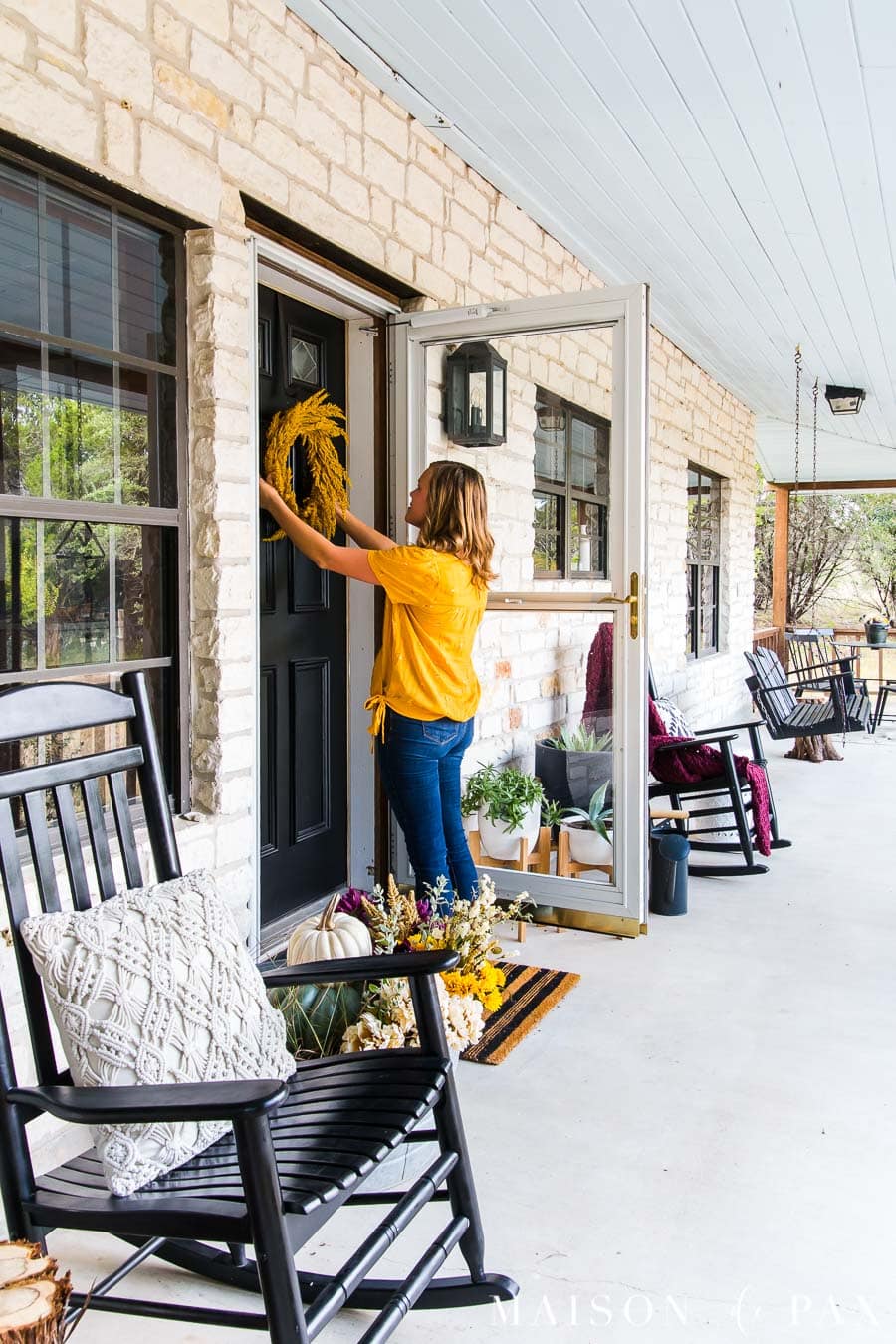 woman hanging fall wreath on front door | Maison de Pax