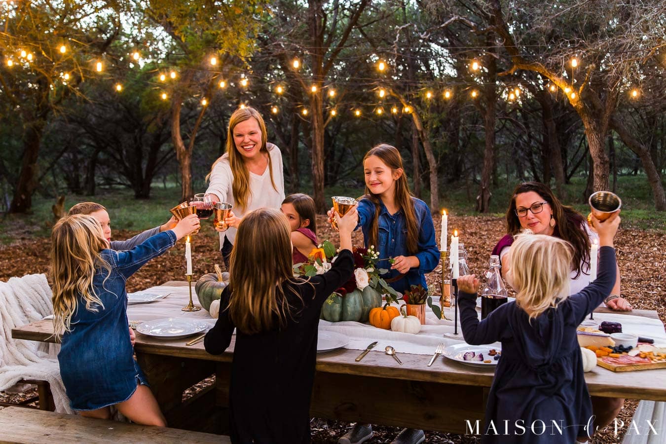 friendsgiving out in the woods with candles and string lights | Maison de Pax