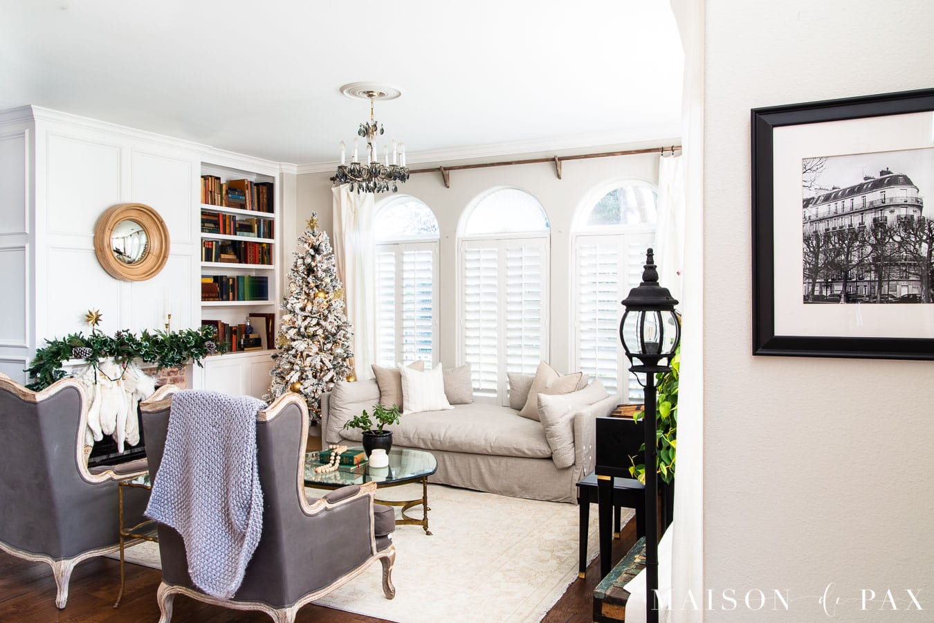white living room with green garland above mantel and flocked tree | Maison de Pax