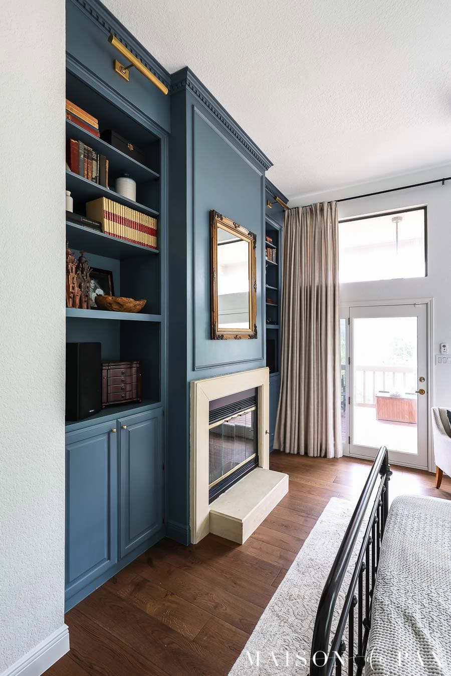 floor to ceiling dark blue bookcases on either side of a limestone fireplace in a bedroom