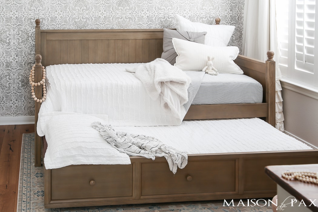 Elegant, neutral little girl room with wood tones and a stenciled accent wall: A gray-washed trundle bed provides the perfect anchor for a gorgeous, neutral yet feminine little girl's room.