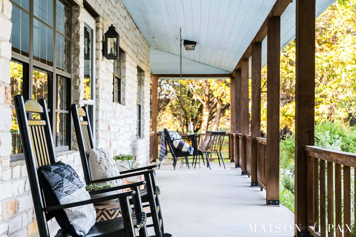 black rocking chairs on a white Austin stone porch with brown cedar posts and railings | Maison de Pax