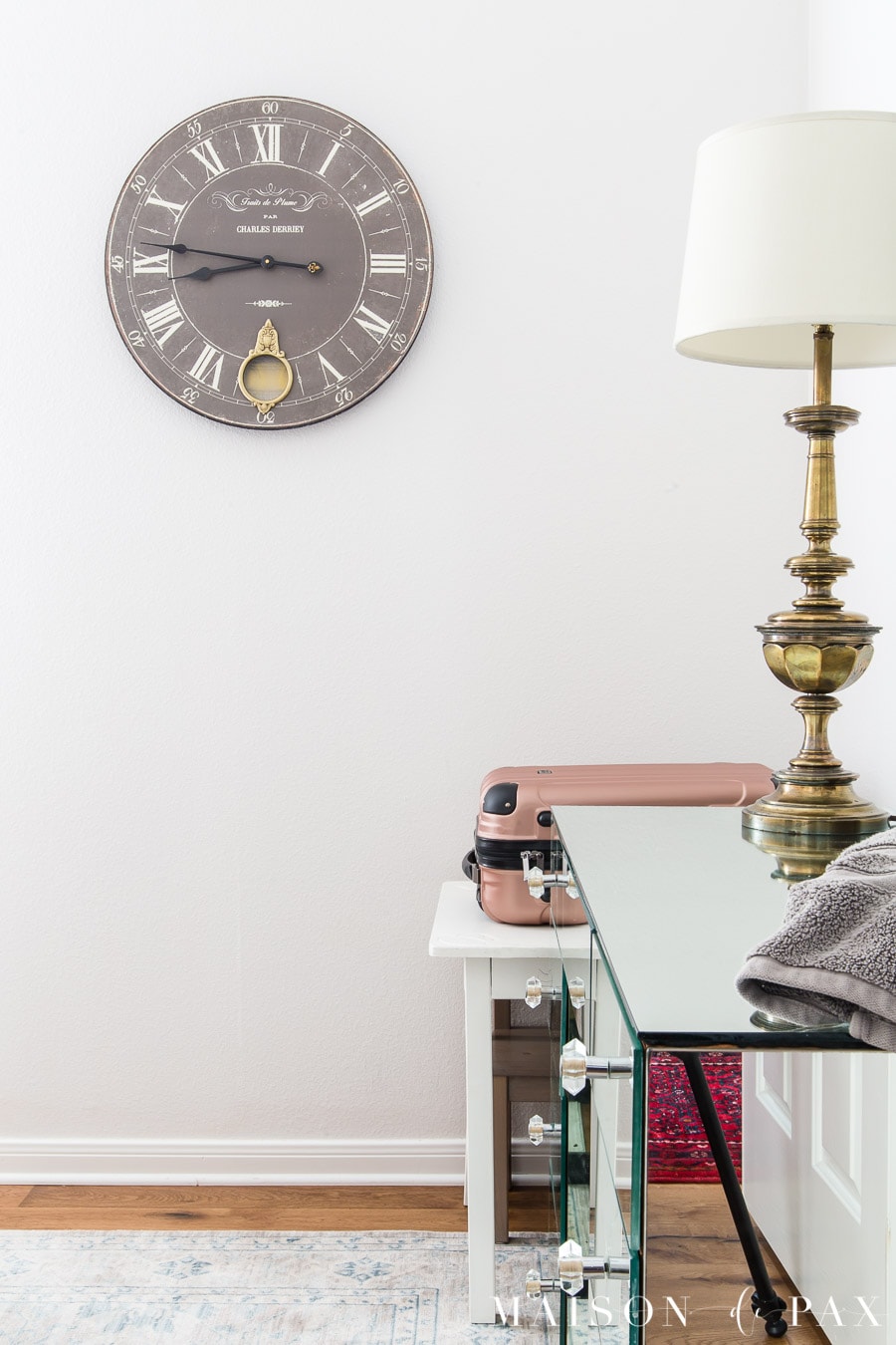 white room with mirrored dresser and pink suitcase