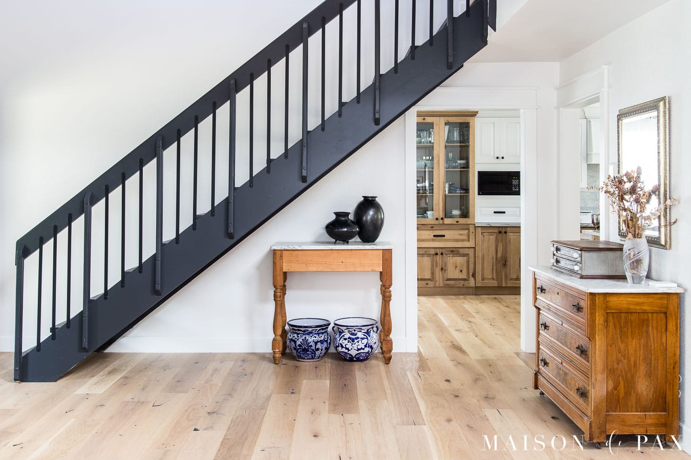 black staircase in white house with light wood floors